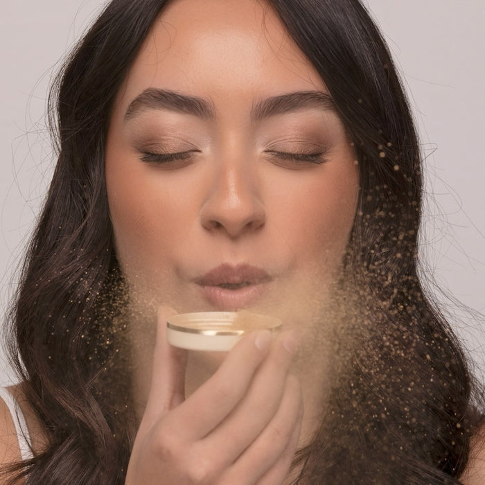 Woman blowing loose mineral makeup from inside a lid