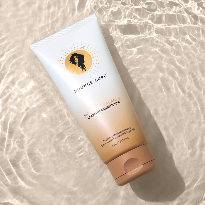 Full-size moisture-balancing Bounce Curl product bottle in water, highlighting its moisturizing feature.