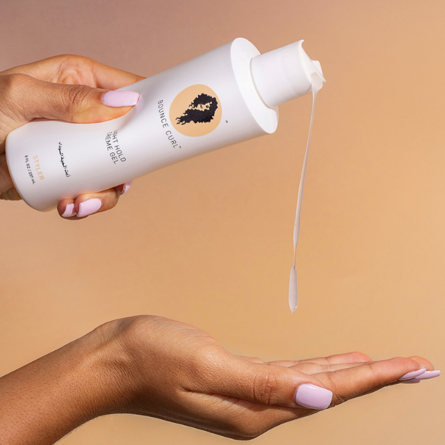 Hand with painted nails squirting Bounce Curl Light Hold Creme Gel into the other hand