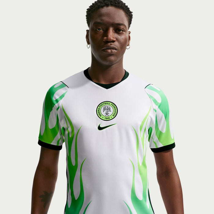 White football jersey with green flame pattern, round Nigeria crest, and Nike swoosh at chest.