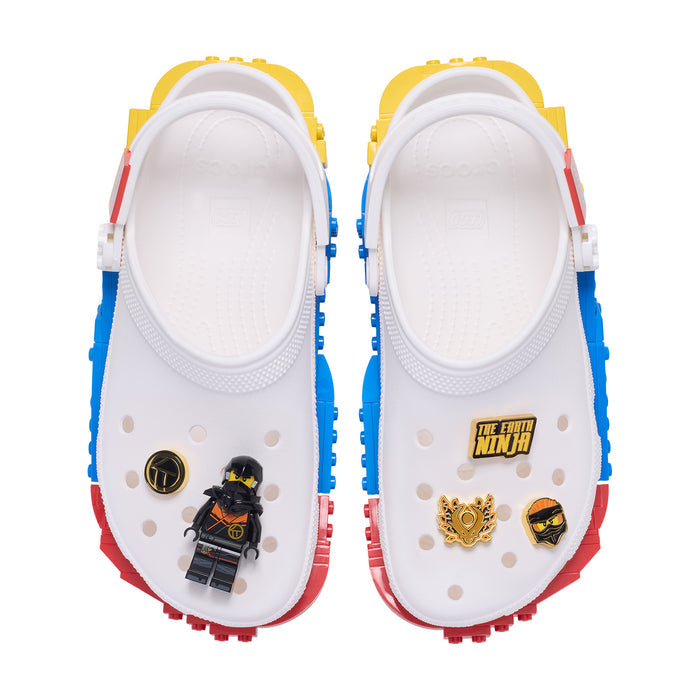White clogs with blue and red sides and 5 LEGO NINJAGO Jibbitz charms