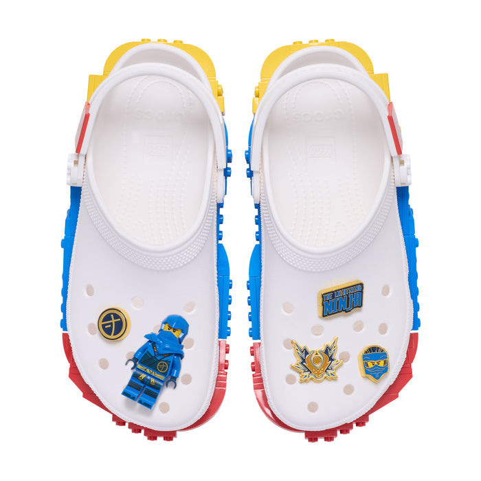 White Crocs with blue and gold Ninjago Jay Jibbitz charms on front strap