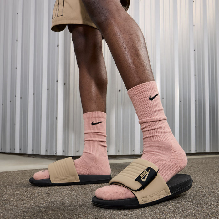 Men's tan slide sandals worn with pink crew socks and black Nike logo strap