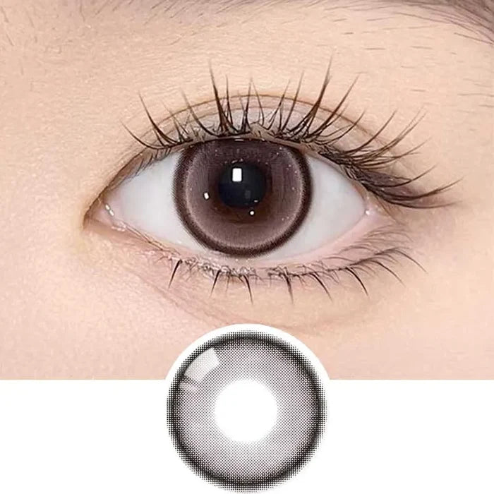 A close-up of a brown eye wearing Olola Meow Natural Angora Pink contacts by Olola, featuring iris-enlarging pink circle lenses and a subtle cat eye effect, with the lens displayed separately below the eye.