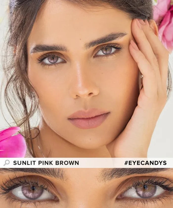 A woman with sunlit pink brown eyeshadow, soft pink lipstick, and EyeCandys Peach Fuzz Bundle (5 Pairs) colored contacts gazes at the camera, touching her face. Pink flowers frame her. Text: "PEACH FUZZ BUNDLE" and "#EYECANDYS".
