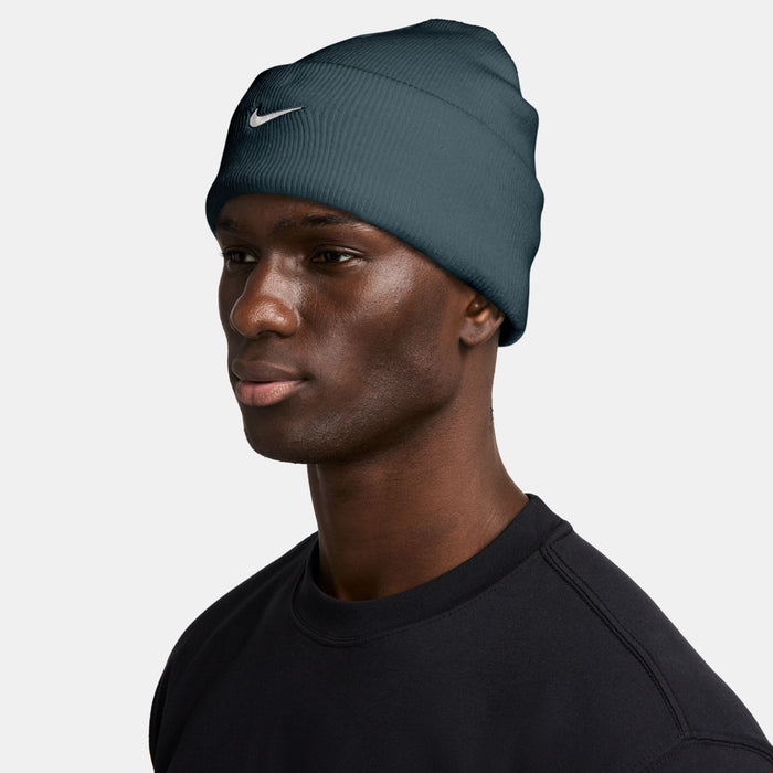 Nike beanie on model, dark teal ribbed knit with small white Swoosh