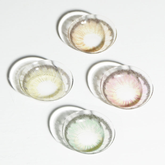Four natural color contact lenses, including EyeCandys Pink Label Angel Green, are arranged on a white surface, with the green lens casting a distinct shadow.