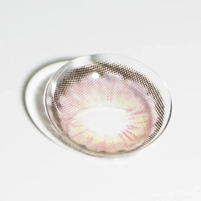 A single EyeCandys Pink Label Angel Pink contact lens, featuring a translucent brown and pink circle lens design, rests on a white surface with a subtle shadow.
