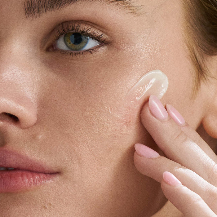 Close-up of a woman applying cream to her face