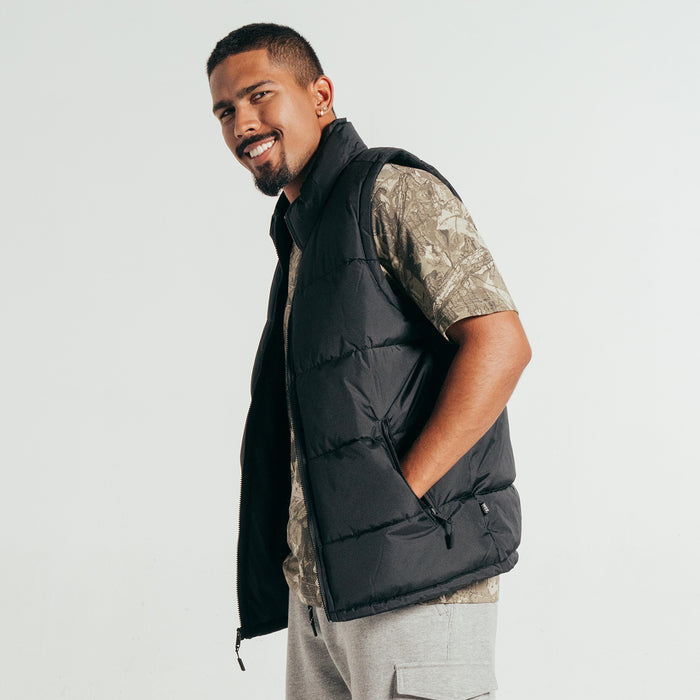 Black quilted puffer vest with zip front and angled side pockets; side view.