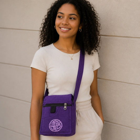 Woman wearing a purple crossbody bag with a logo against a beige wall