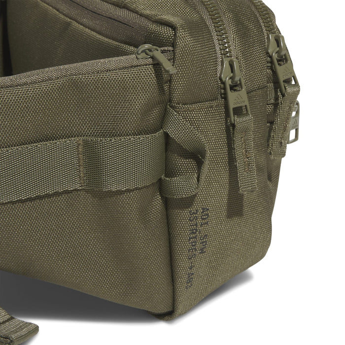 Olive crossbody bag side view with zippers, stitched panels, and webbing pocket