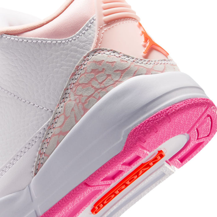 Kids' sneaker side close-up with white leather, gray patterned panel, pink outsole edge.