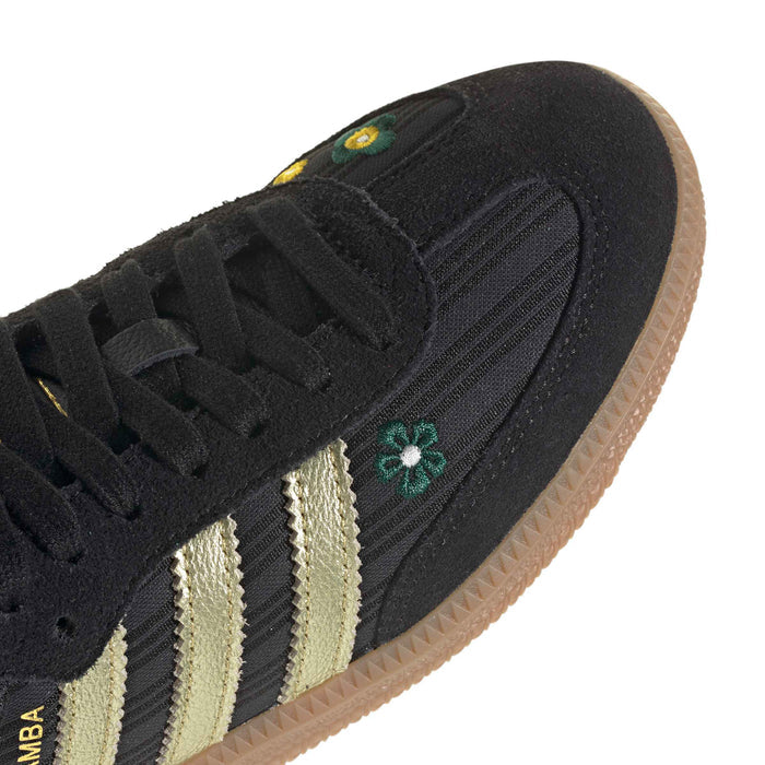 Close-up of women’s black Samba sneaker side with gold stripes and small floral logos