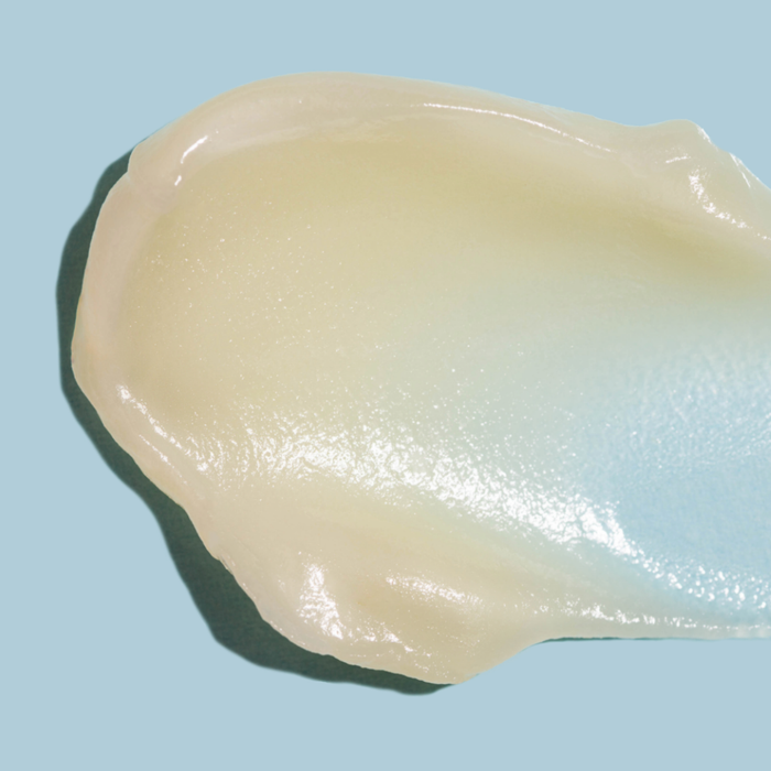 SKN144 SKNLOGIC Derma Repair Balm | A dollop of translucent, creamy cosmetic balm with a glossy finish, shown against a solid light blue background.