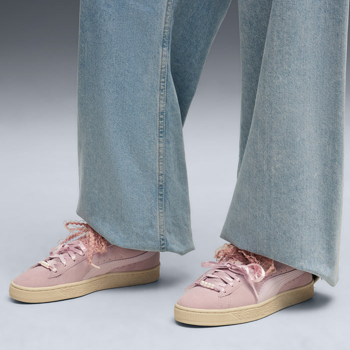 Women’s pink suede lace-up sneakers worn with light blue wide-leg jeans