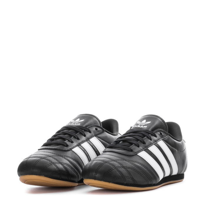 Pair of women's black taekwondo sneakers with white stripes and gum sole, adidas