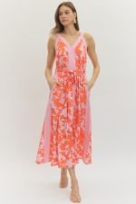 Entro Tangerine Dreams Dress displayed on a hanger showing its vibrant orange color and flowing fabric design.