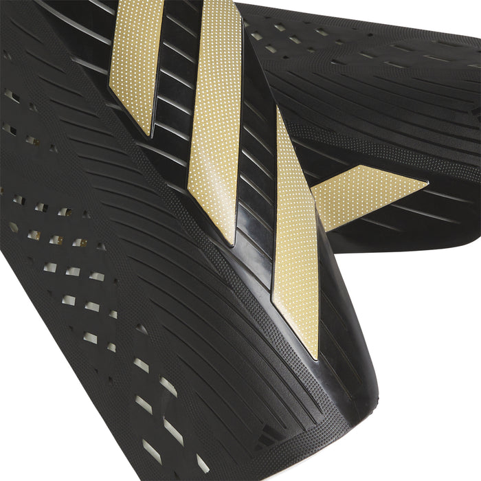 Black slip-in shin guard with gold diagonal accents and vented textured surface
