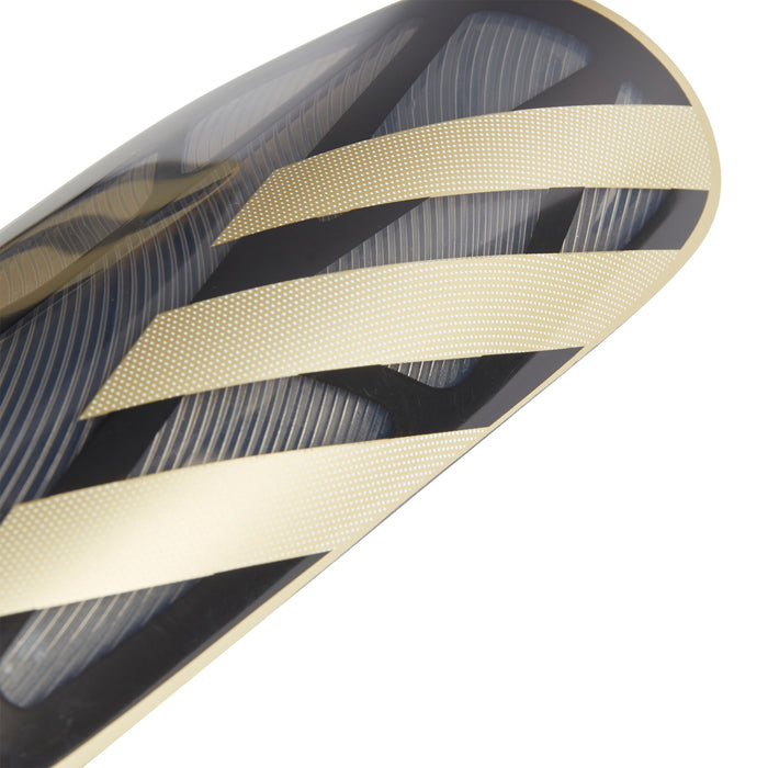 Black shin guard shell with metallic gold diagonal stripes and textured lines