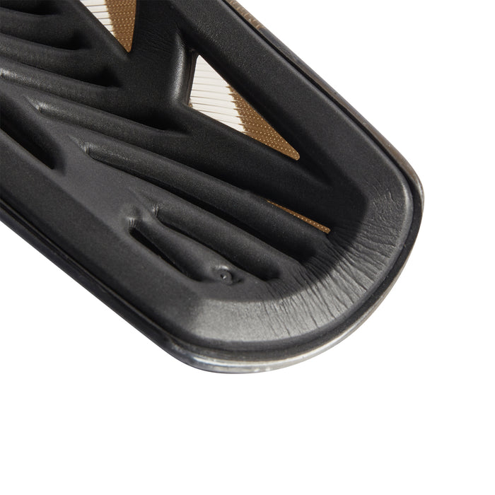 Black shin guard with vented ridges and curved edge, metallic gold inlay