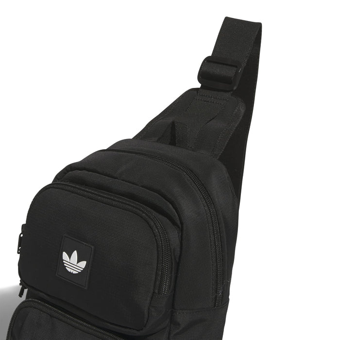 Black utility sling bag side view with adjustable strap and front zip pouch