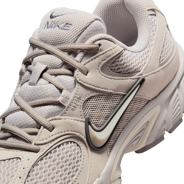 Men's beige Nike running shoe upper close-up with swoosh, laces, and textured mesh.