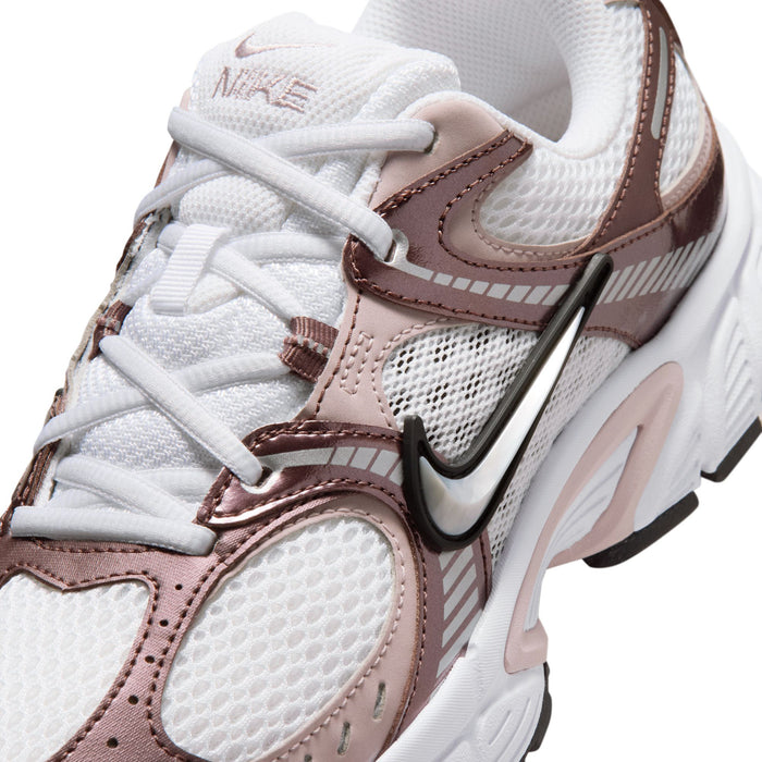 Women’s sneaker close-up: white laces, mesh upper, rose-brown overlays, and swoosh