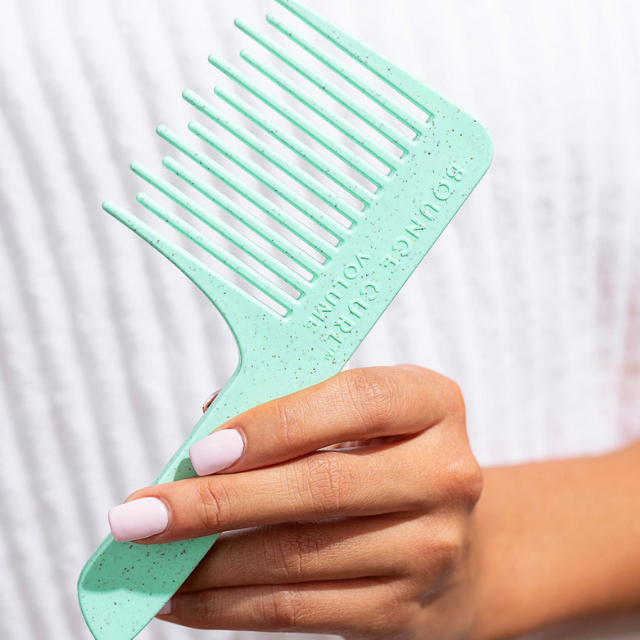 Woman holding a Bounce Curl square top wide tooth hair comb.