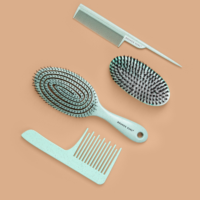 Four light blue Bounce Curl brushes and combs site on a tan background.