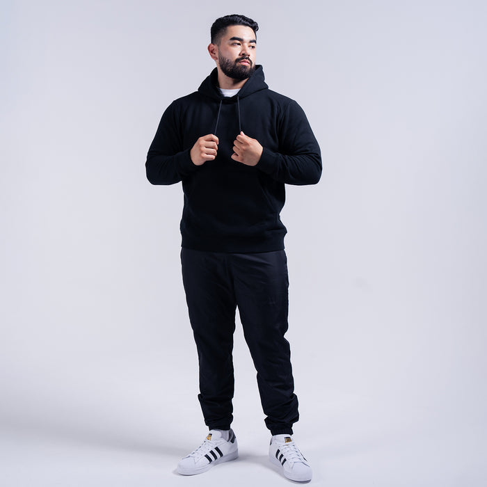 Black wind pants on model, elastic cuffs and tapered fit