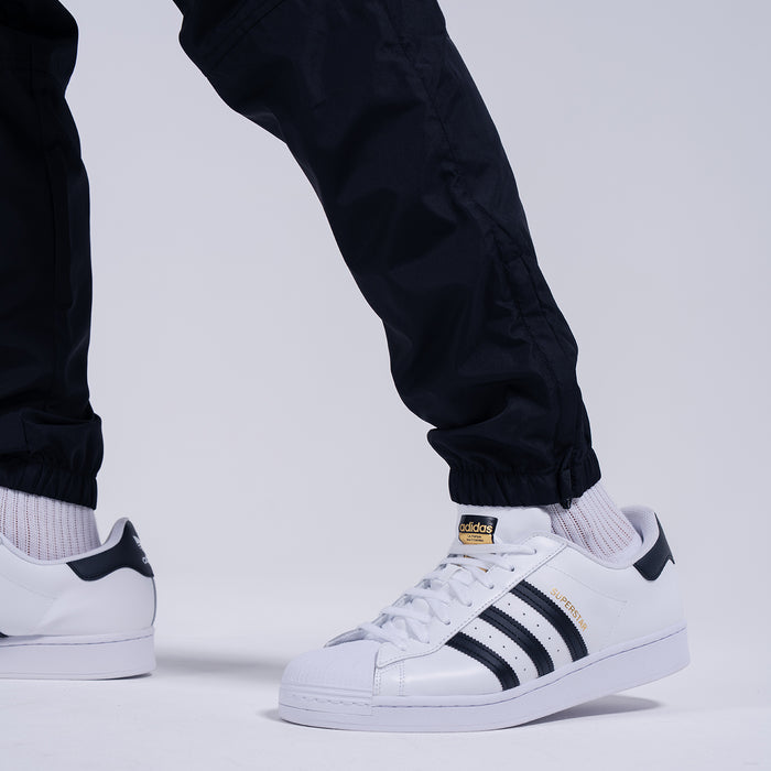 Black tapered wind pants with elastic ankle cuffs